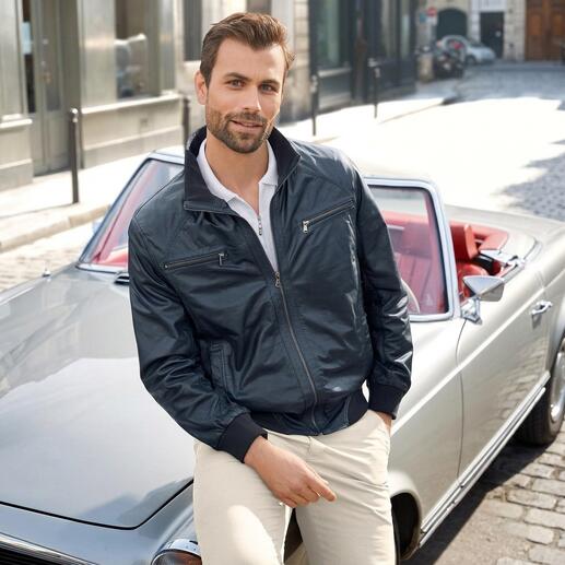 Mann posiert im blauen Sommer-Lederblouson vor einem Auto.