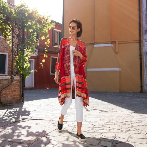 Frau in Rot mit IVKO Kimono-Strickjacke, läuft auf einem gepflasterten Platz