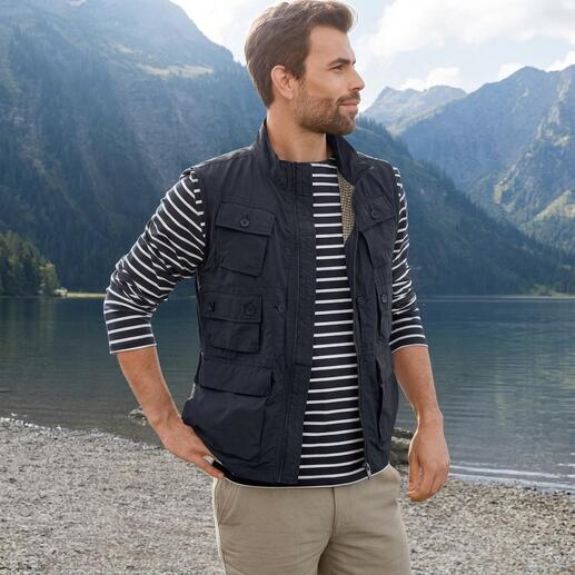 Mann in schwarzer 10-Taschen-Weste schaut auf einen Bergsee.