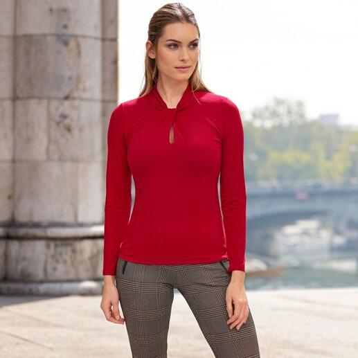 Frau in rotem Tencel-Shirt mit Schlüsselhalsschlitz vor urbanem Hintergrund.