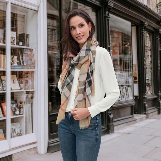 Frau trägt Lochcarron Tartan-Schal in Camel, vor einem Geschäft.