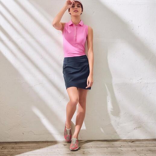 Frau in rosa Oberteil und Rock mit bunten Flecht-Sneakern, in heller Umgebung.