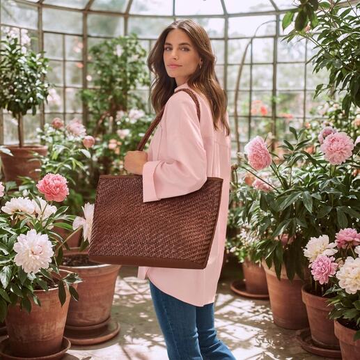 Frau mit rosa Oversize-Bluse und großer Tasche in Gewächshaus
