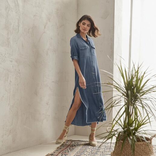Frau in Jeansblusen-Kleid mit Schlitz steht in einer Pose.
