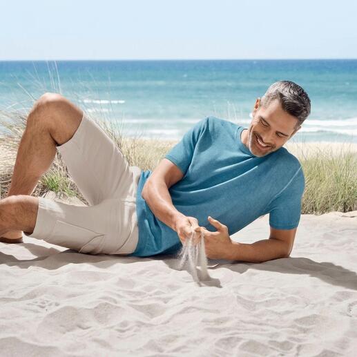 Mann in hellblauem Junghans Ice-Piqué-Shirt am Strand, beim Spielen mit Sand