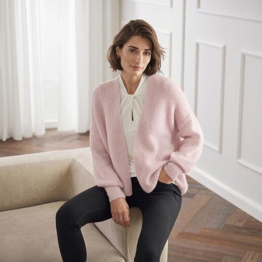 Frau sitzt im Junghans 1954 Flausch-Cardigan in rosa.