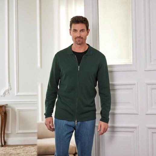 Mann in grüner Jacke und schwarzem T-Shirt mit einem Lächeln.