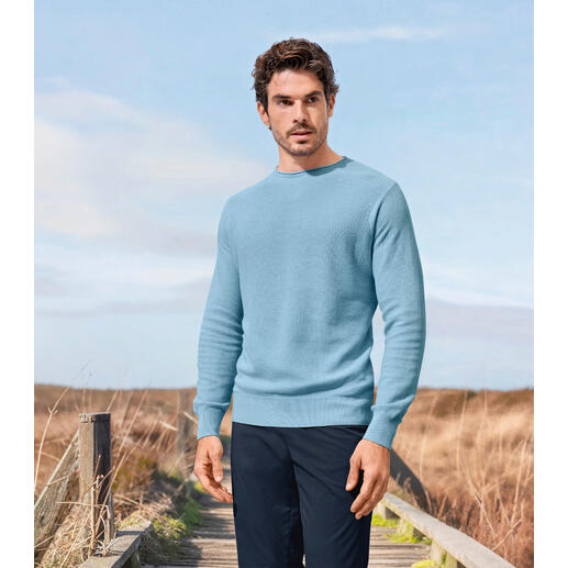 Junghans 1954 Edel-Piqué-Pullover Mann in einem hellblauen Edel-Piqué-Pullover steht in einer ländlichen Umgebung.