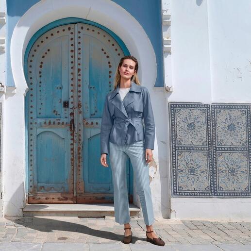 Frau in einer blauen Lammnappa-Jacke vor einer blauen Tür
