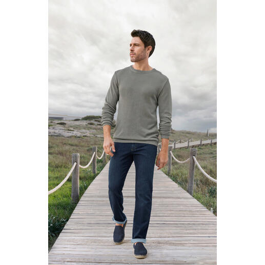 Greige Mann in einem grauen Ivanhoe Tencel-Piqué-Pullover und Jeans auf einem Holzsteg.