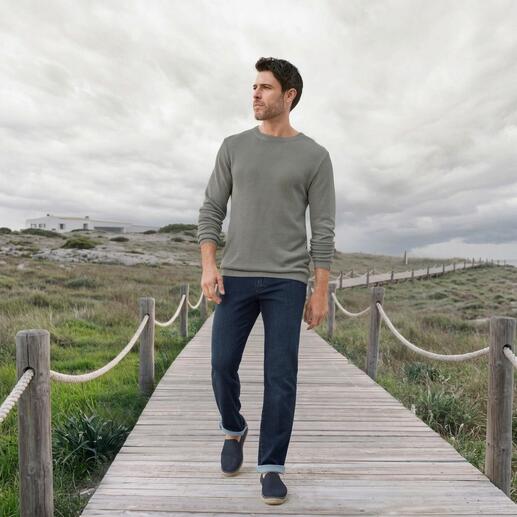 Mann in einem grauen Ivanhoe Tencel-Piqué-Pullover und Jeans auf einem Holzsteg.