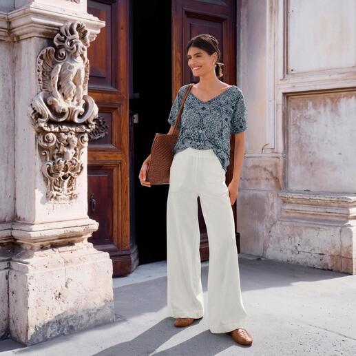 Frau in IVKO Ornament-Strickshirt mit floralem Muster und weißen Hosen