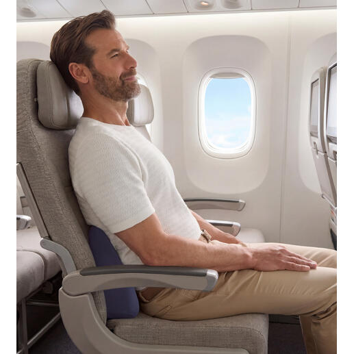 Mann sitzt im Flugzeug mit einem Reise-Rückenkissen zur Unterstützung des Rückens.