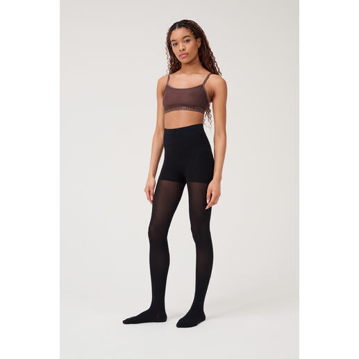 Frau trägt schwarze Beauty-Strumpfhose mit brauem Oberteil.