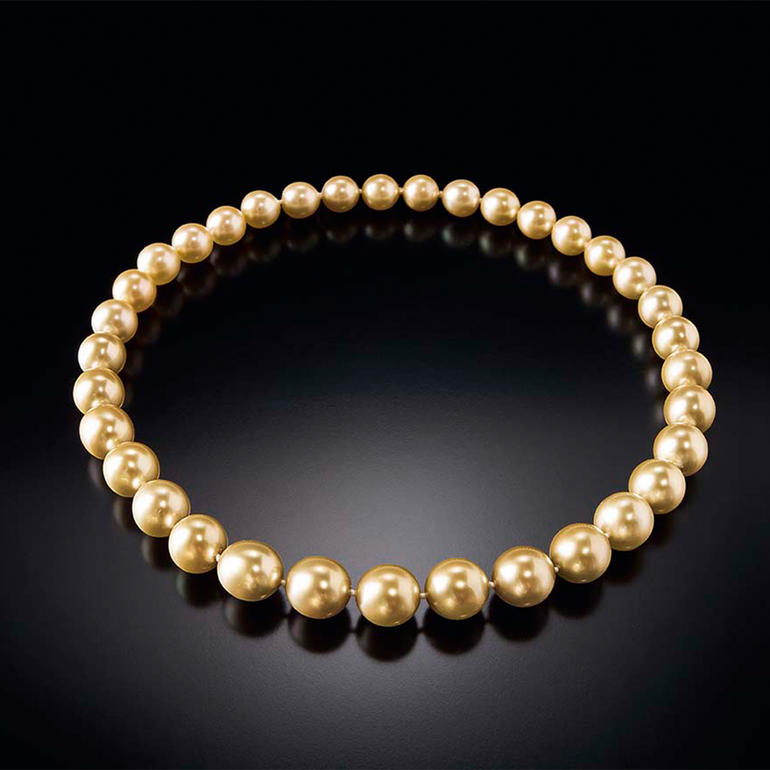 Goldenes Südsee-Zuchtperlen-Collier auf schwarzem Hintergrund.