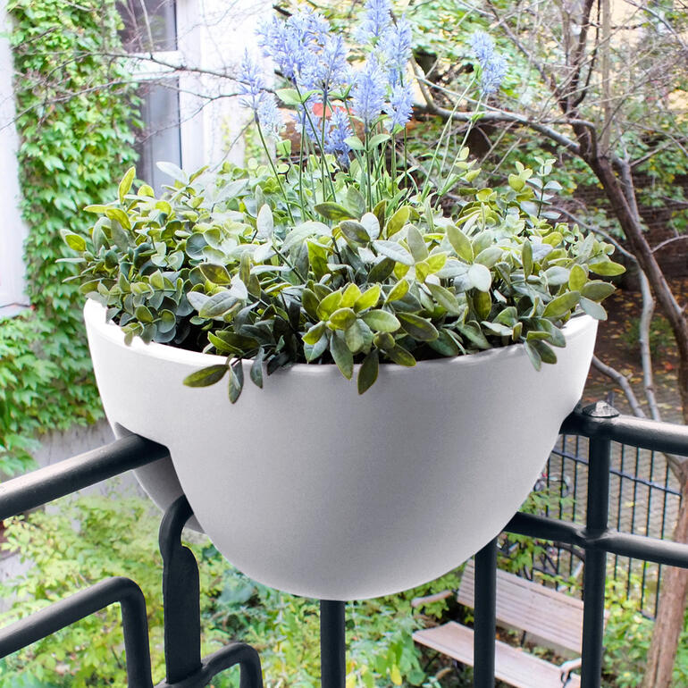 Eck-Geländer-Pflanztopf mit grünen Pflanzen auf einem Balkon.