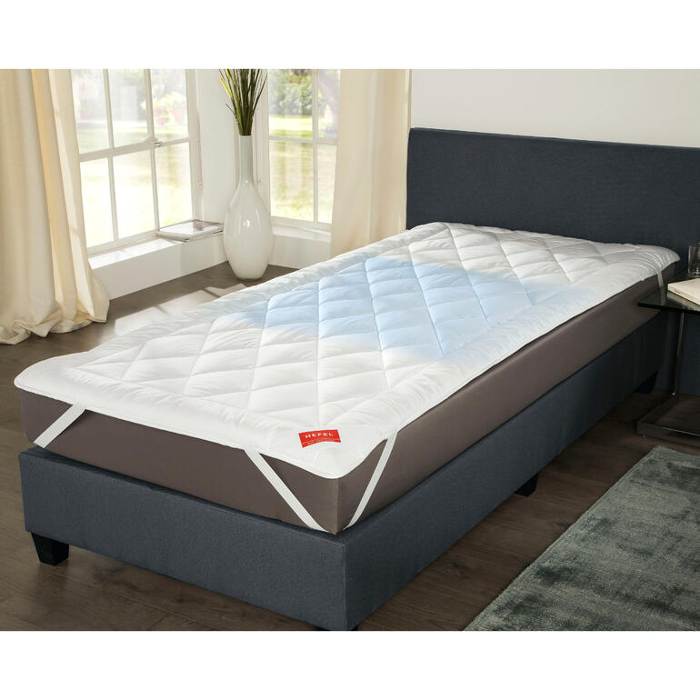 Hefel Cool Unterbett auf einem Bett in einem hellen Raum.