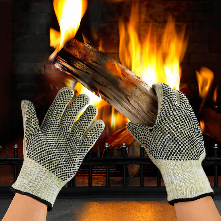 Hitzeschutz-Handschuhe halten ein Holzstück vor einem Feuer.