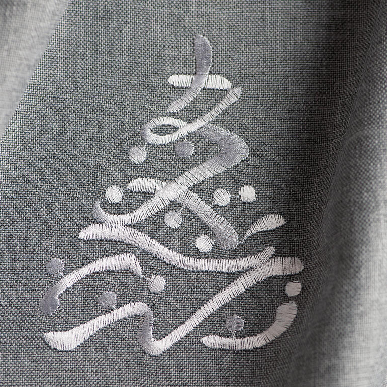 Detailaufnahme einer stickten Weihnachtsbaum-Motiv auf Tischdecke.