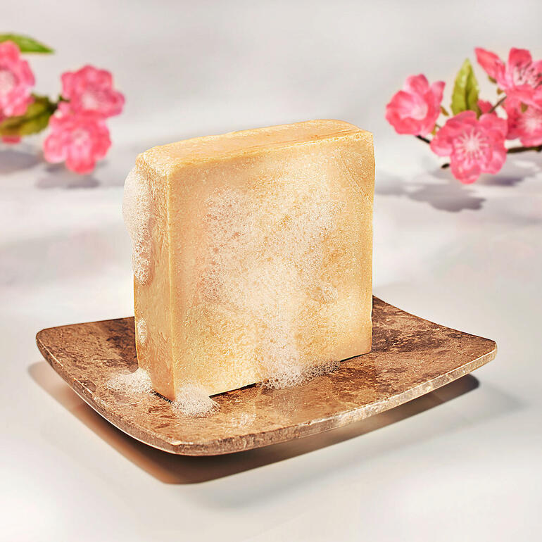 Hautmilchseife mit Blüten auf einem dekorativen Teller.