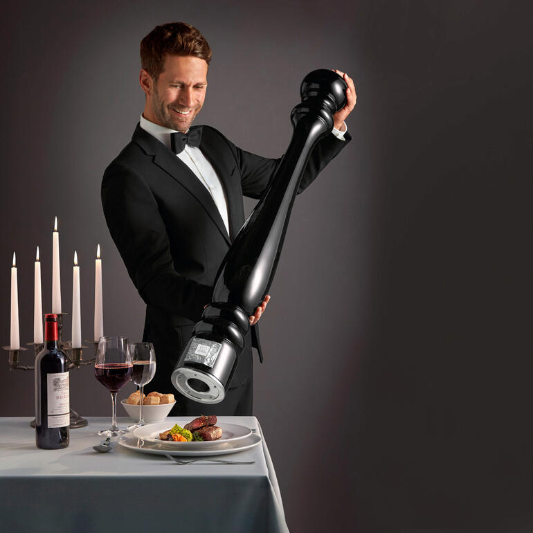 Mann mit übergroßer Pfeffermühle beim Servieren