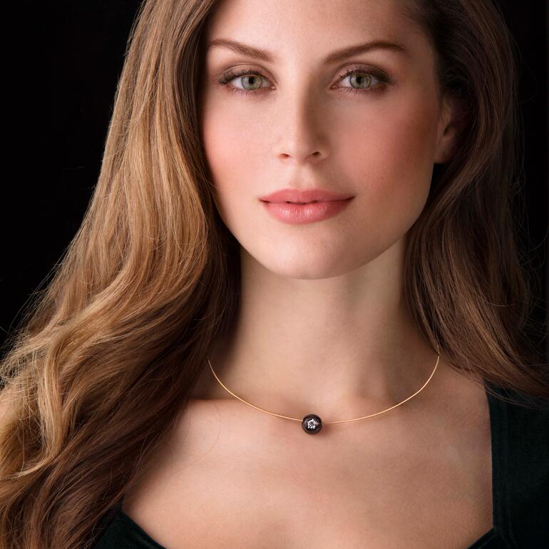 Diamant-Perlen-Collier Frau trägt Diamant-Perlen-Collier vor dunklem Hintergrund