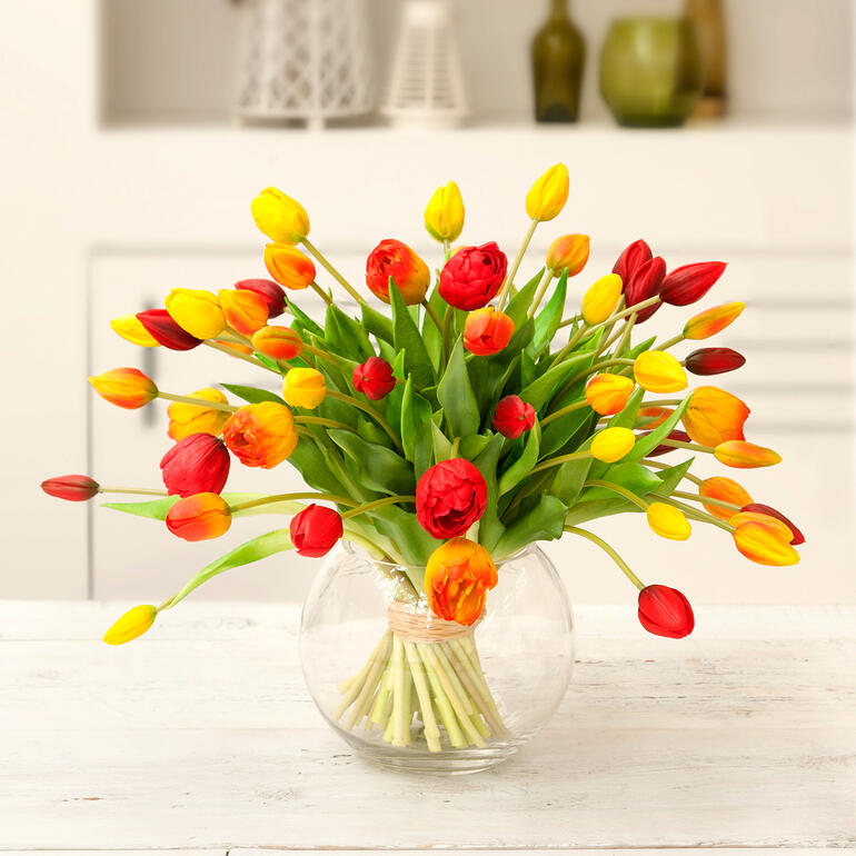 Bunter Tulpenstrauß in einer runden Glas Vase.