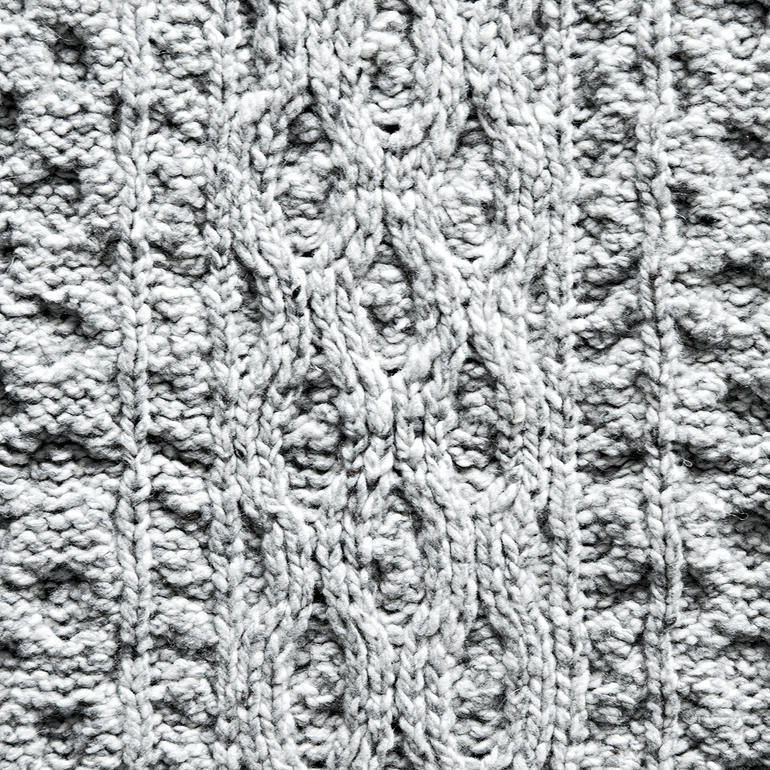 Nahaufnahme des Strickmusters eines grauen Plaids.