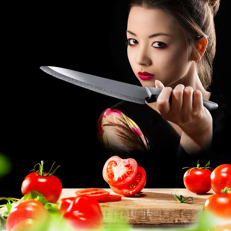 Person mit Zirkonia-Keramik-Messer schneidet frische Tomaten auf einem Holzbrett.
