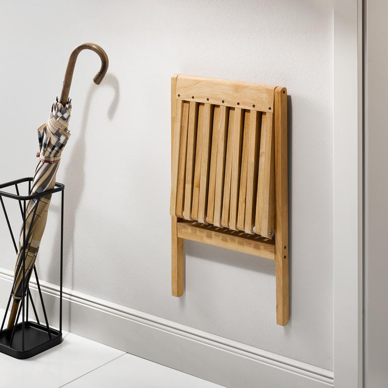 Zusammengeklappter Falt-Wandhocker an der Wand.