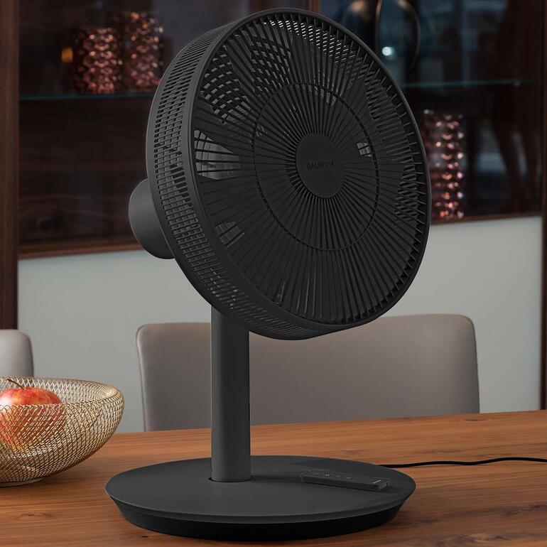 In einem Ihr kompakter Tischventilator. Dazu einfach das untere Säulenstück ausklicken. Schwarzer Design-Ventilator auf einem Tisch in einer eleganten Umgebung