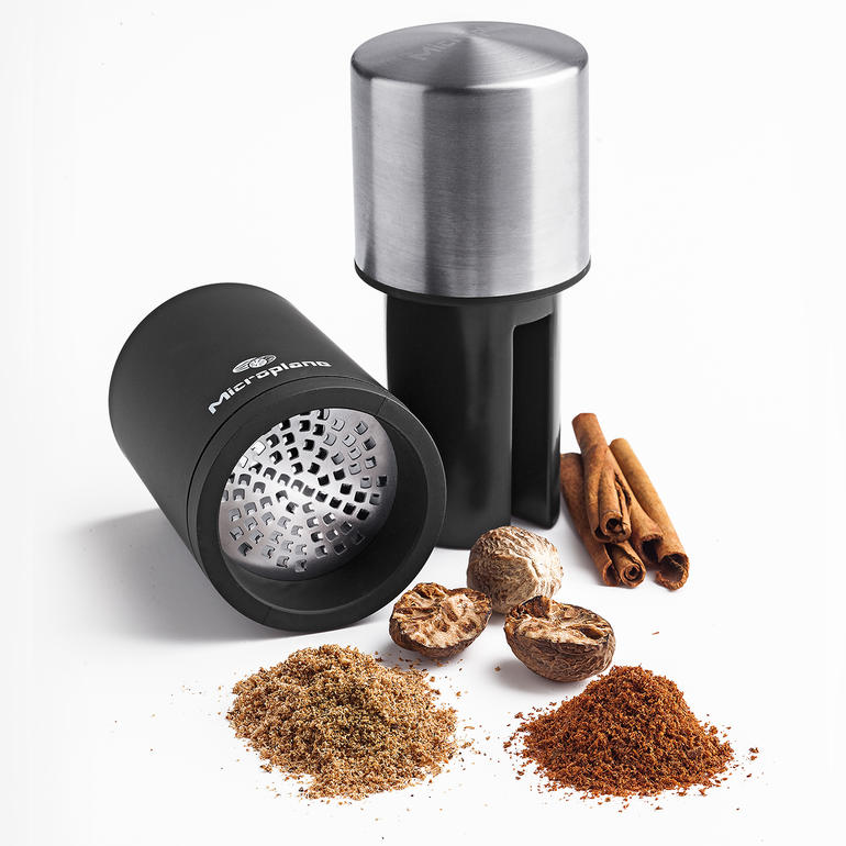 Microplane Muskatmühle mit Gewürzen auf einem weißen Hintergrund.