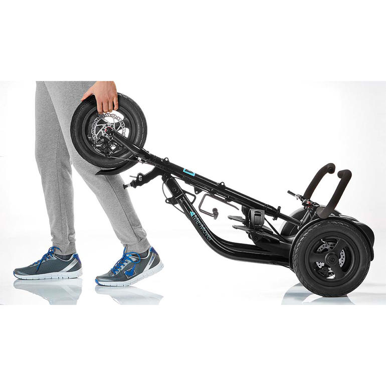 Mit 2 Handgriffen gefaltet. Bequem wie ein Trolley zu ziehen. Me-Mover Fitnessgerät wird von einer Person auf einem Gehweg getragen.
