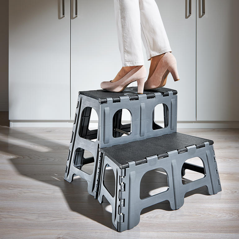 Eine Person steht auf einem 2-Stufen-Klapptritt in einer modernen Küche.