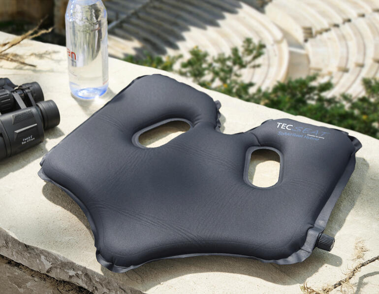 Bequemer SoftAirSeat auf einem Stein mit Wasserflasche und Fernglas.