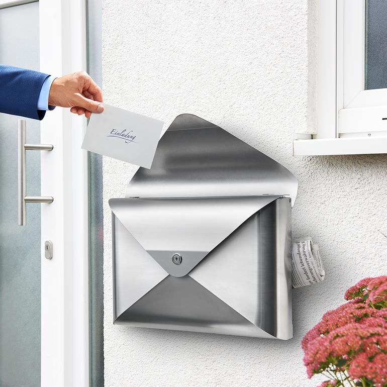 Hand steckt einen Brief in einen modernen Briefkasten