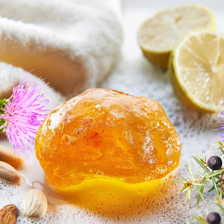 Bernsteinseife mit Zitrusfrüchten und Blumen auf einem Handtuch.