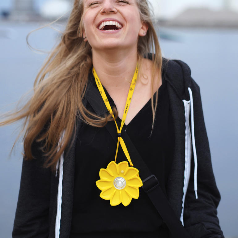 Frau trägt eine gelbe Solarlampe um den Hals und lächelt.