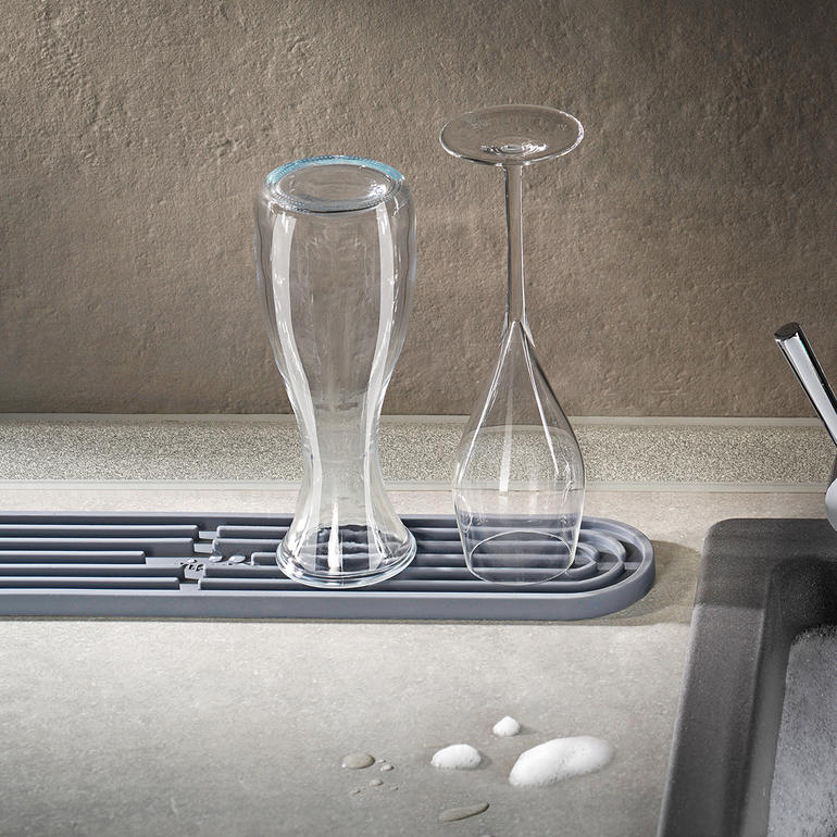 Gläser trocknen auf einer grauen Abtropfmatte.