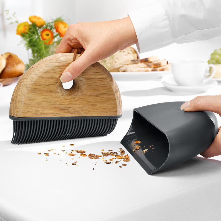 Nutzer mit Sweep Tischkehr-Set entfernt Krümel von einem Tisch.