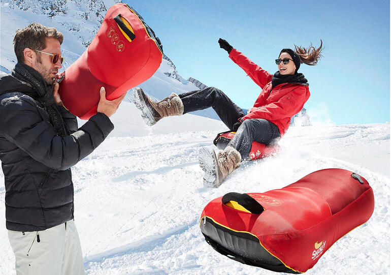 Frau rutscht mit Luftkissen-Bob Snokey einen Schneeberg hinunter