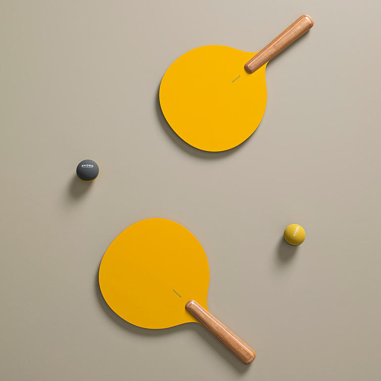 Zwei handgefertigte gelbe Beachball-Raquettes und zwei Bälle auf einem Untergrund.