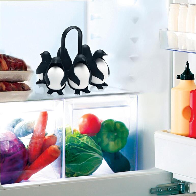 Eierhalter in Form von Pinguinen im Kühlschrank auf einer Glasablage.