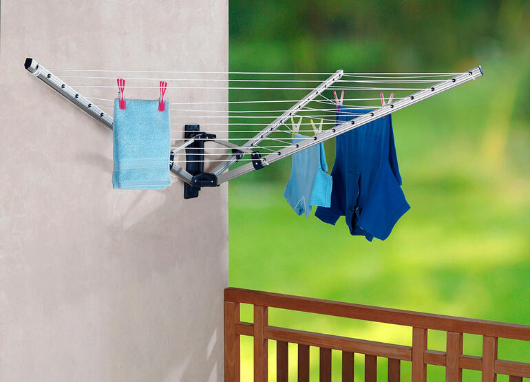 Faltbare Wand-Wäschespinne mit Wäsche aufgezogenen Kleidungsstücken.