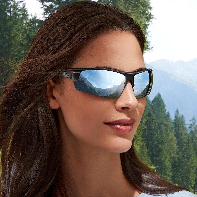 Frau mit uvex Sonnenbrille und braunen Haaren steht im Freien