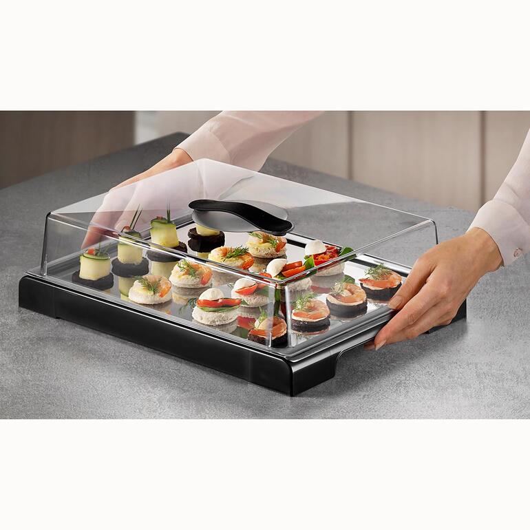 Die gekühlte Edelstahlplatte hält Ihre Speisen bis zu 4 Stunden appetitlich frisch. Hände platzieren Speisen auf einer gekühlten Frischhalteplatte mit Deckel