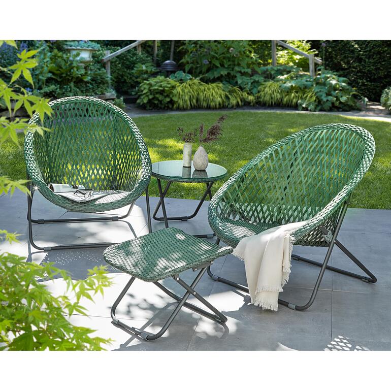 Faltbarer Fußhocker in grün, Teil des Loungesets, auf einem Gartenboden neben zwei Sesseln.