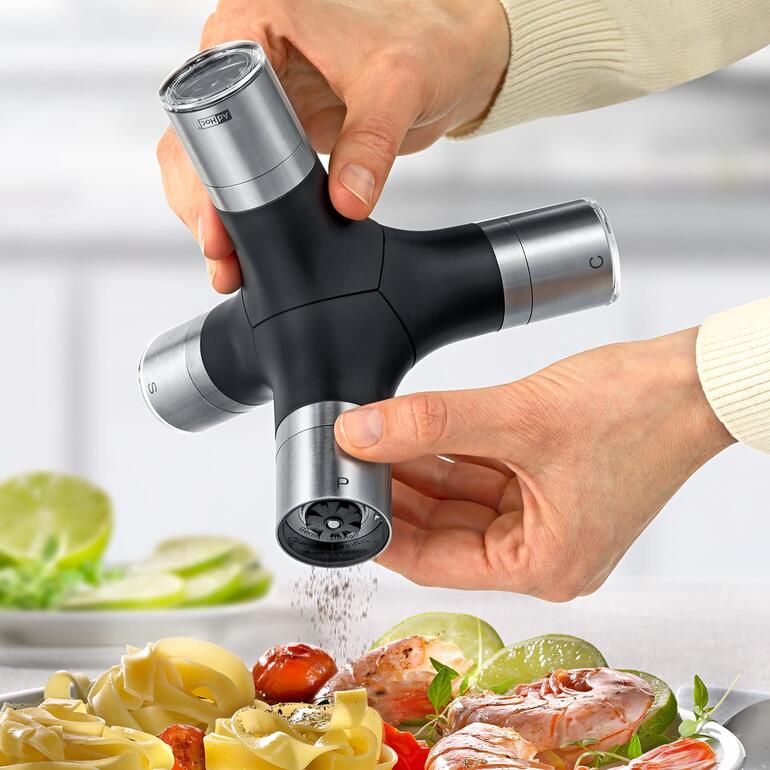 AdHoc Multi-Gewürzmühle in Gebrauch, Gewürze werden über einem Gericht verteilt.
