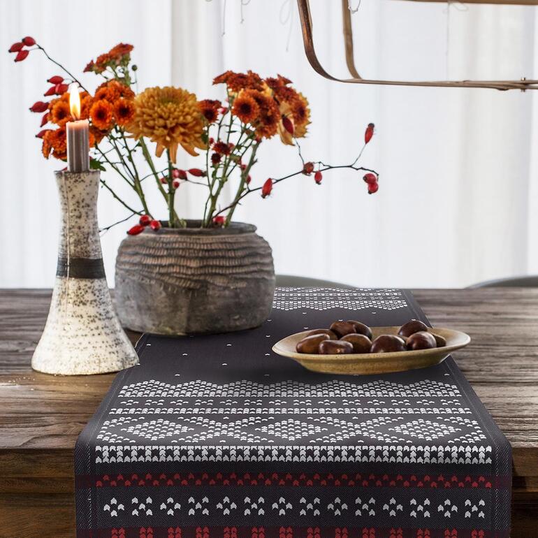 Tisch mit schwarzem Tischläufer Norwegen, Kerze und Blumenstrauß.