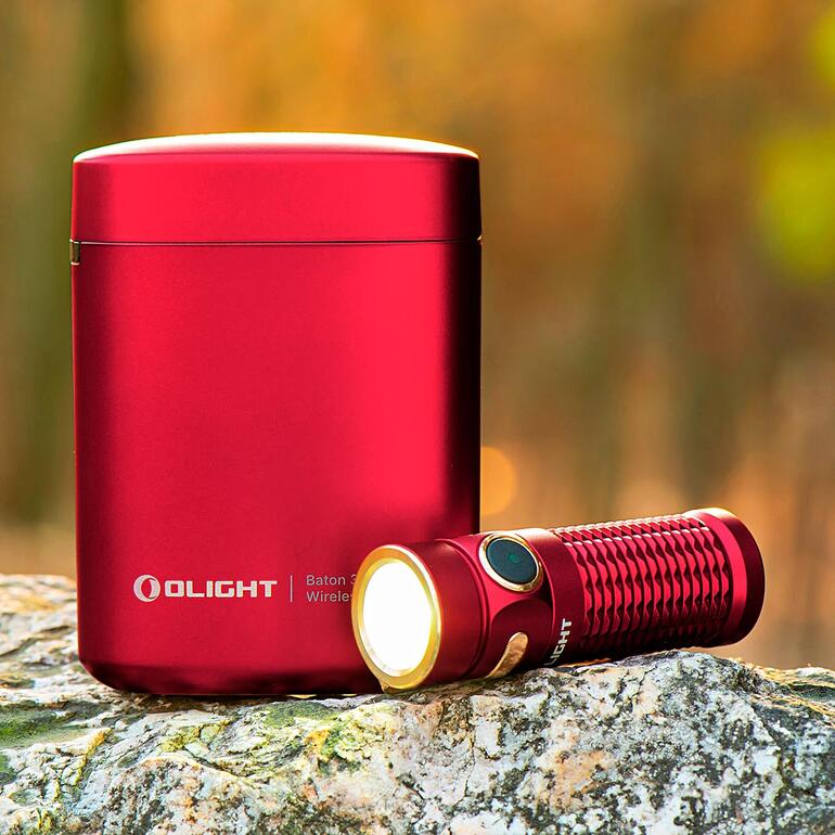 Olight Baton 3 Taschenlampe mit rotem Lade-Etui auf einem Stein